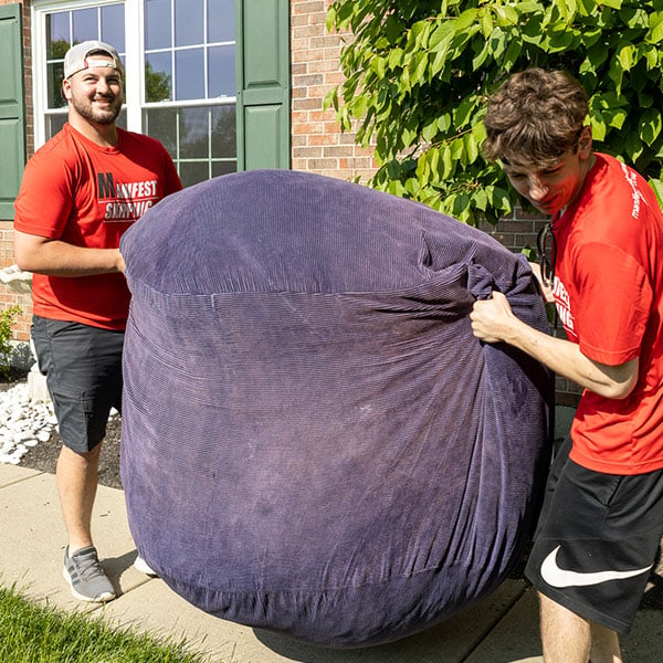 two movers wearing red shirts and black shorts moving a large object